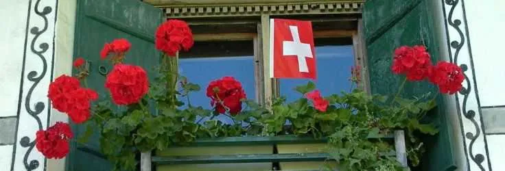 Swiss flag and red flowers on a traditional house window